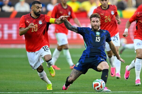 Egypt's Mohamed Salah (10) runs beside Brazil's Léo Pereira (15) during an international friendly soccer match in Cleveland, Saturday, June 6, 2026. (AP Photo/David Richard)