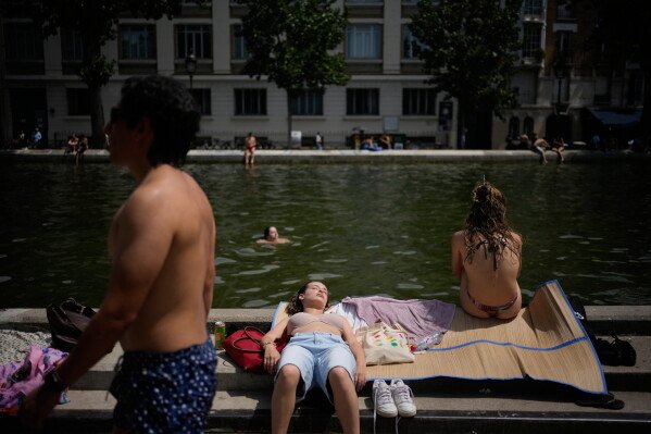 Parisians bath in the Canal Saint-Martin in Paris, as the national weather service, Meteo France, placed 54 departments, about half the country, under a red heat wave alert, Tuesday, June 23, 2026. (AP Photo/Christophe Ena )