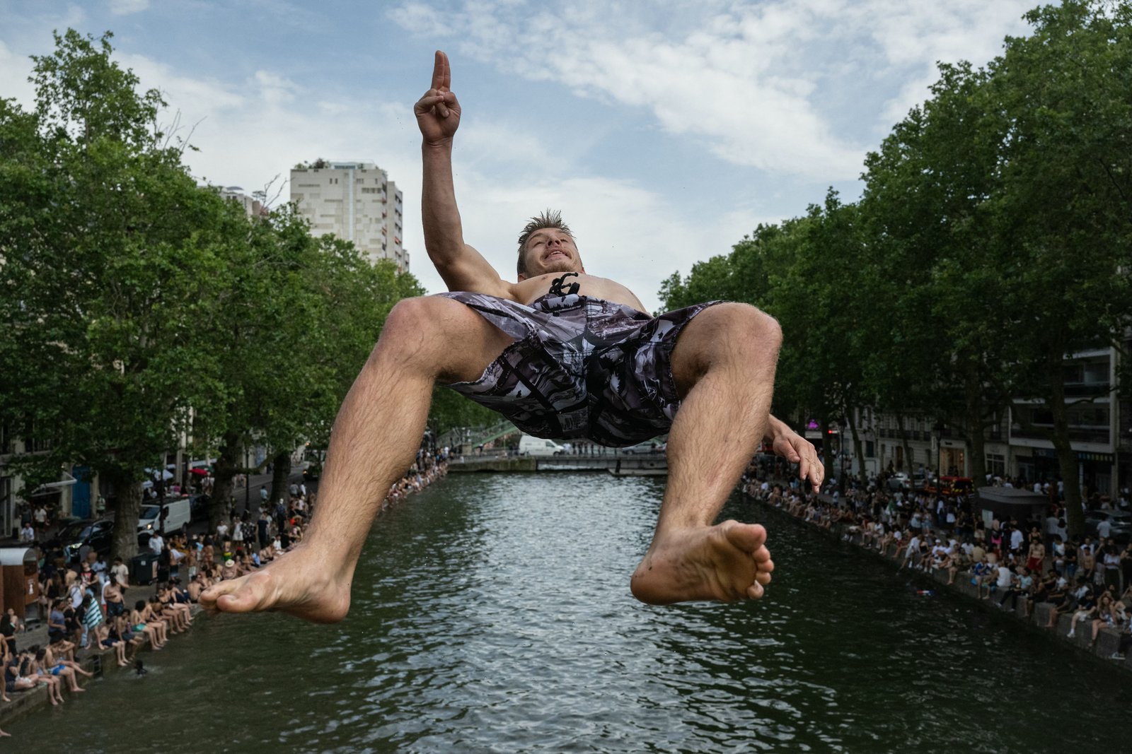 TOPSHOT - A swimmer dives into the Canal Saint-Martin, from an unapproved spot for swimming as France experiences a heatwave in Paris on June 20, 2026. Due to the ongoing heatwave sweeping across France - the Bassin des Recollets - a portion of the Canal Saint-Martin in the French capital has been opened for swimming from June 17. France issued a red heatwave alert across more than a third of the country for June 21, as a ferocious heatwave dug in and the government banned the consumption of alcohol in certain areas during the annual Fete de la Musique festivities. (Photo by ARNAUD FINISTRE / AFP via Getty Images)