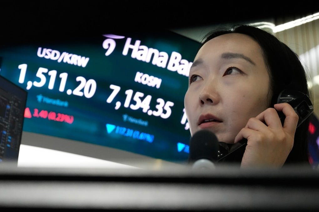 A currency trader talks on the phone near a screen showing the Korea Composite Stock Price Index (Kospi) and US dollar exchange rate in Seoul. Photo: AP