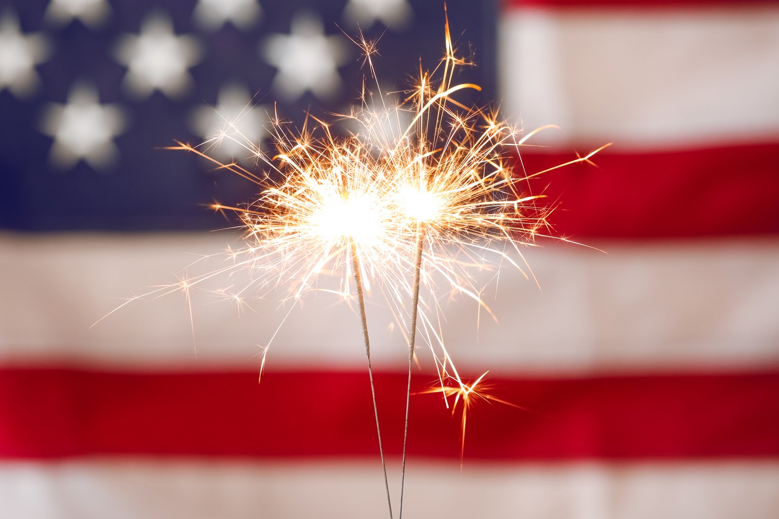 Bright burning sparklers against American flag, closeup