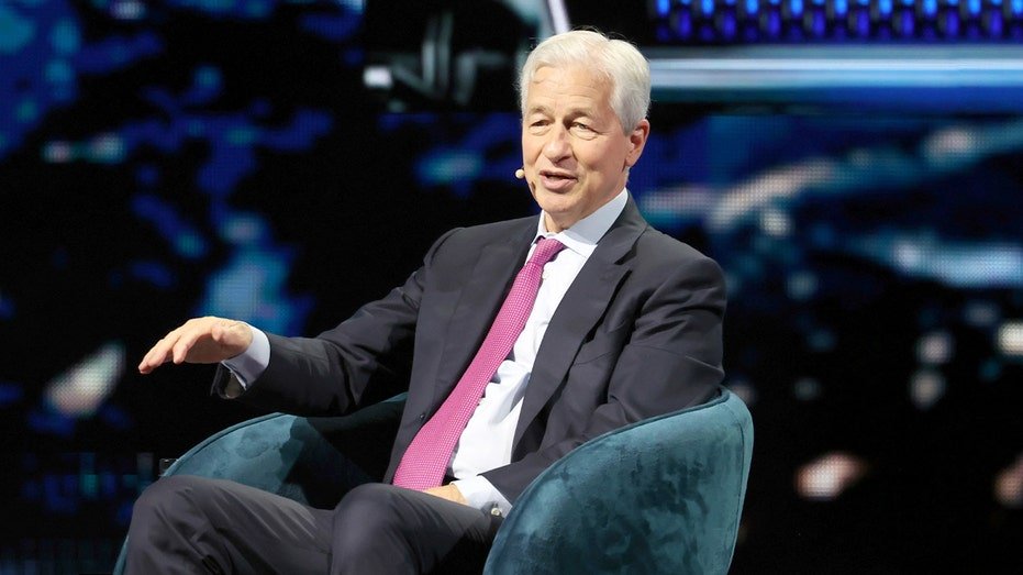Banking executive addresses an audience from a stage at a large indoor arena.