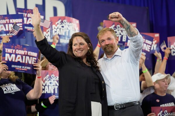 Democratic U.S. Senate candidate Graham Platner, right, and his wife Amy Gertner gesture to supporters during a primary election night watch party June 9, 2026, in Blue Hill, Maine. (AP Photo/Robert F. Bukaty, File)