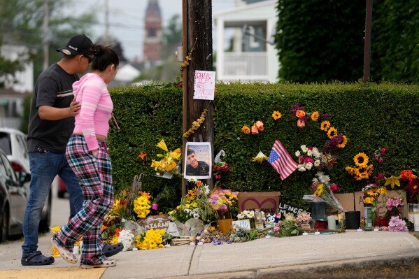 Local residents walk by a makeshift memorial to the victim of a shooting involving U.S. Immigration and Customs Enforcement, Tuesday, July 14, 2026 in Biddeford, Maine. (AP Photo/Robert F. Bukaty)
