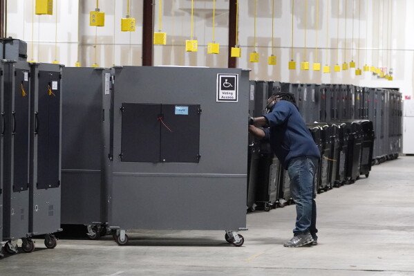 A worker returns voting machines to storage at the Fulton County Election preparation Center Nov. 4, 2020, in Atlanta. (AP Photo/John Bazemore, File)