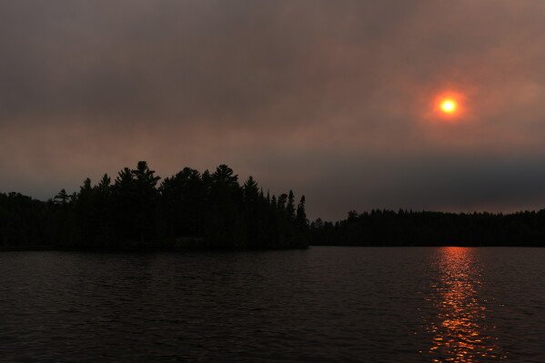 Thick smoke from the Camp Fire hangs in the air over Moose Lake as multiple wildfires burning in the Boundary Waters Canoe Area Wilderness prompted its closure and evacuation Tuesday, July 14, 2026 in Ely, Minn. (Anthony Souffle/Minnesota Star Tribune via AP)