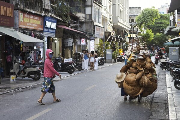 A woman walks toward a street vendor selling bamboo items in Hanoi's Old Quarter. Hanoi, Vietnam, Wednesday, June 24, 2026 (AP Photo/Aniruddha Ghosal) 