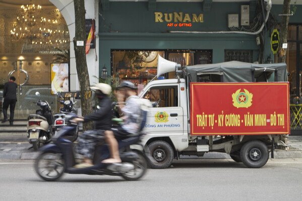 A motorbike drives past a police van that patrols the Old Quarter in Hanoi to clear pavements in Hanoi, Vietnam, Wednesday, June 24, 2026 (AP Photo/Aniruddha Ghosal)  