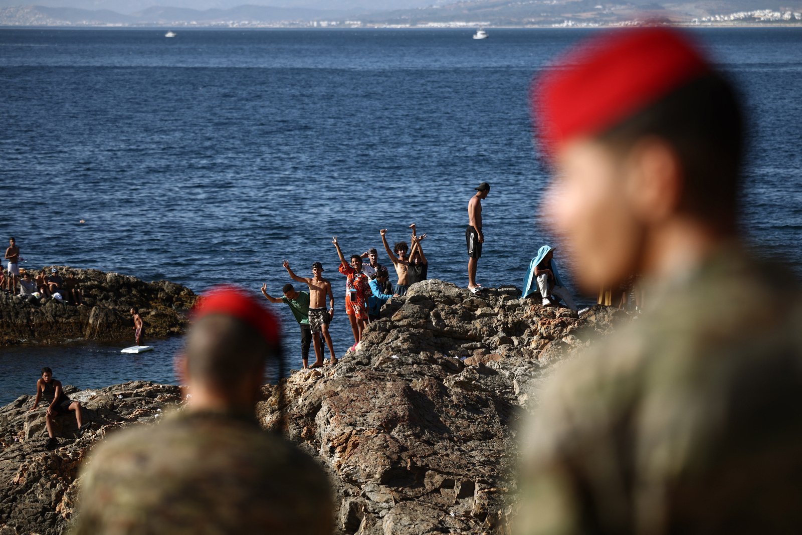 TOPSHOT - Members of the Spanish Army's 'Regulares' infantry forces watch a group of migrants near the border post of the Spanish enclave of Ceuta on August 2, 2026. At least 72 people died during last week's mass influx of migrants into Spain's Ceuta enclave, when tens of thousands of people mostly swam around the border post from Morocco, local officials said today. Most of the estimated 60,000 people who rushed into Spain's north African territory have returned to Morocco since the territory's largest mass migrant crossing. (Photo by Henry NICHOLLS / AFP via Getty Images)