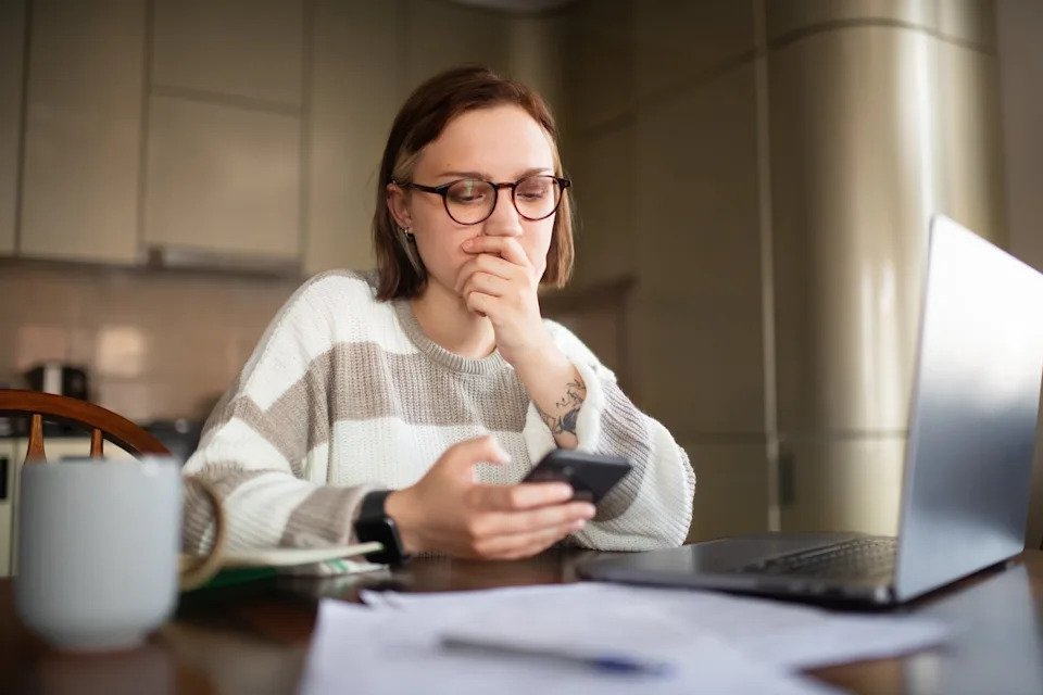A person deep in thought, looking at their phone.