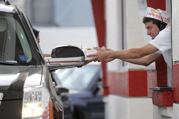 A customer receives her burger and fries from the drive-thru at In-N-Out Burger on Friday, June 11, 2010, in the Hollywood area of Los Angeles. (AP Photo/Adam Lau)