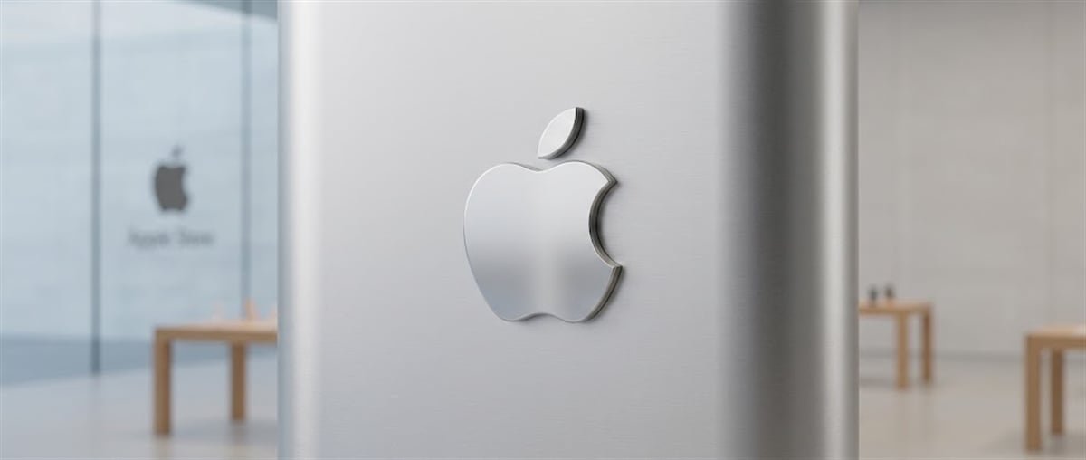 Metallic Apple logo mounted on a pillar inside an Apple Store, with the storefront glass entrance visible in the background.