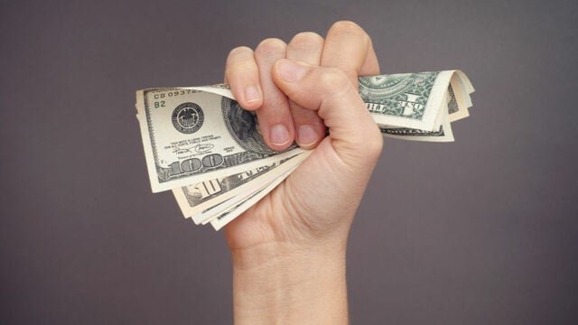 Woman hand squeezes dollar bills